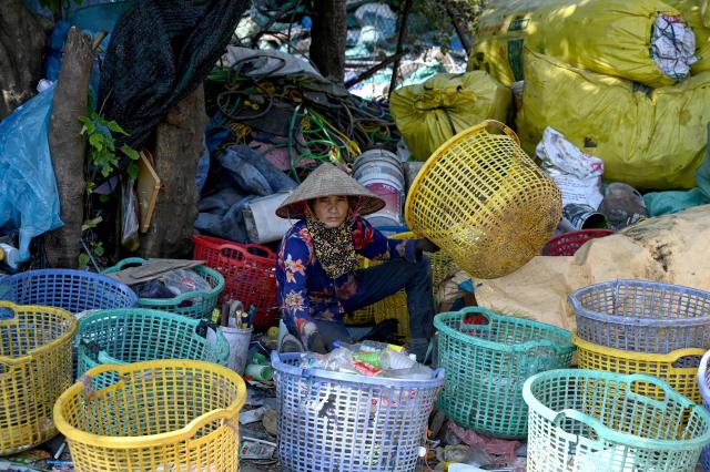 This photo taken on November 25, 2025 shows a woman sorting plastic waste in a village on the outskirts of Hanoi. (Photo by Nhac NGUYEN / AFP)