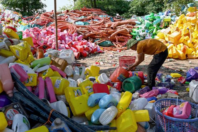 This photo taken on November 25, 2025, shows a man working at a plastic waste dump in a village on the outskirts of Hanoi. (Photo by Nhac NGUYEN / AFP)
