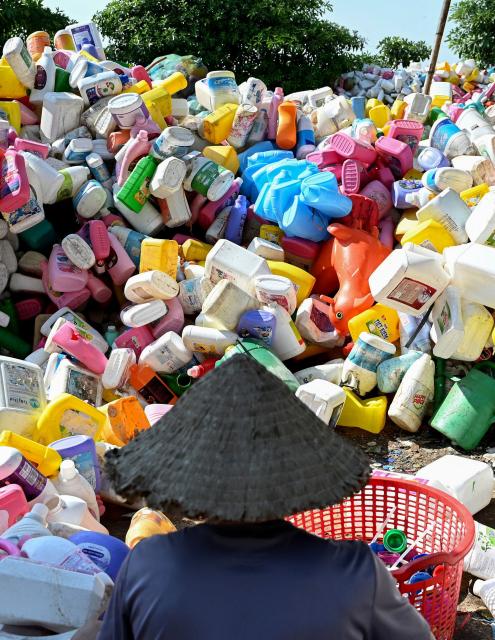 This photo taken on November 25, 2025, shows a man working at a plastic waste dump in a village on the outskirts of Hanoi. (Photo by Nhac NGUYEN / AFP)