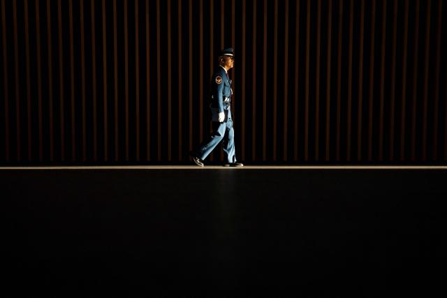 A security worker walks in a ray of light at the Tokyo International Forum in Tokyo on December 4, 2025. (Photo by Yuichi YAMAZAKI / AFP)