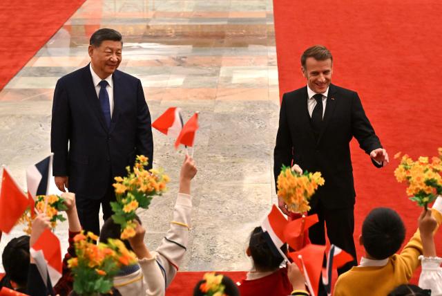 France’s President Emmanuel Macron (R) gestures towards children next to China’s President Xi Jinping (L) during a welcome ceremony at the Great Hall of the People in Beijing on December 4, 2025. (Photo by Adek BERRY and ADEK BERRY / POOL / AFP)