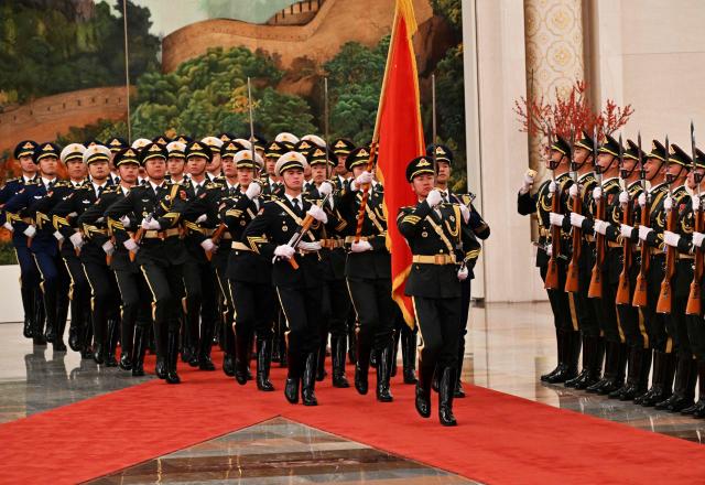 Honour guards march as China’s President Xi Jinping receives France’s President Emmanuel Macron during a welcome ceremony at the Great Hall of the People in Beijing on December 4, 2025. (Photo by Adek BERRY and ADEK BERRY / POOL / AFP)