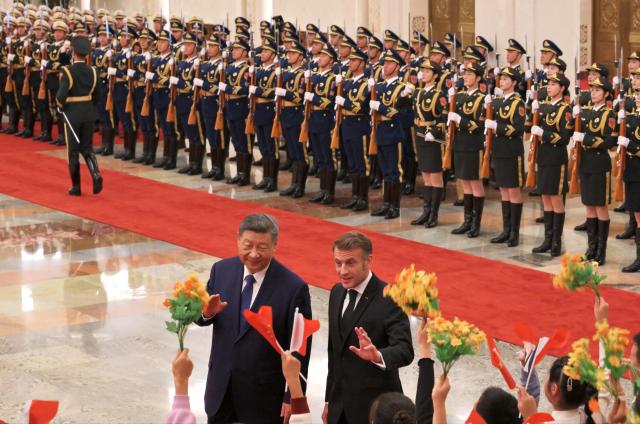 France’s President Emmanuel Macron (R) gestures towards children next to China’s President Xi Jinping (L) during a welcome ceremony at the Great Hall of the People in Beijing on December 4, 2025. (Photo by Adek BERRY and ADEK BERRY / POOL / AFP)