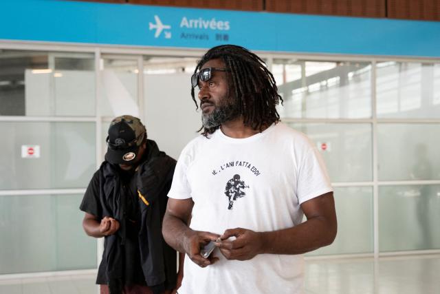 Pro-independence activist Dimitri Quenegei waits for the arrival of Kanak pro-independence leader Christian Tein (L), head of the CCAT (Cellule de Coordination des Actions de Terrain), at the Noumea - La Tontouta international airport in La Tontouta, south of Noumea, in France's Pacific territory of New Caledonia, on December 4, 2025. (Photo by Delphine MAYEUR / AFP)