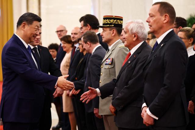 China's President Xi Jinping, alongside France's President Emmanuel Macron, meets former French prime minister Jean-Pierre Raffarin during a welcome ceremony at the Great Hall of the People in Beijing on December 4, 2025. (Photo by Sarah Meyssonnier / POOL / AFP)