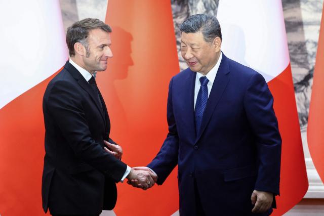 China's President Xi Jinping (R) and France's President Emmanuel Macron shake hands following a signing ceremony for agreements at the Great Hall of the People in Beijing on December 4, 2025. (Photo by Sarah Meyssonnier / POOL / AFP)