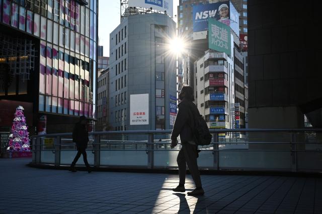 A woman walks on a path in the late afternoon in Shibuya, in Tokyo on December 4, 2025. (Photo by GREG BAKER / AFP)