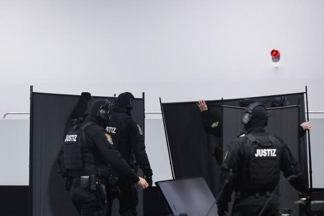 Judicial security officers set up privacy screens in front of the bulletproof glass box for Saudi Arabian defendant Taleb Jawad al-Abdulmohsen in the temporary courtroom in Magdeburg, eastern Germany on December 04, 2025, during his trial over the deadly Christmas market attack in December 2024. The Saudi doctor went on trial accused of driving an SUV through a Christmas market, killing six people and wounding more than 300. Taleb Jawad al-Abdulmohsen, a 51-year-old psychiatrist, was arrested next to the battered rental vehicle after the attack on December 20, 2024 in the eastern city of Magdeburg. (Photo by RONNY HARTMANN / AFP)