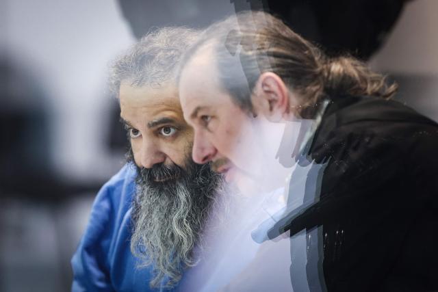Saudi Arabian defendant Taleb Jawad al-Abdulmohsen (L) speaks to his lawyer Thomas Rutkowski as he waits inside a bulletproof glass box in the temporary courtroom in Magdeburg, eastern Germany on December 4, 2025, during his trial over the deadly Christmas market attack in December 2024. The Saudi doctor went on trial accused of driving an SUV through a Christmas market, killing six people and wounding more than 300. Taleb Jawad al-Abdulmohsen, a 51-year-old psychiatrist, was arrested next to the battered rental vehicle after the attack on December 20, 2024 in the eastern city of Magdeburg. (Photo by RONNY HARTMANN / AFP)