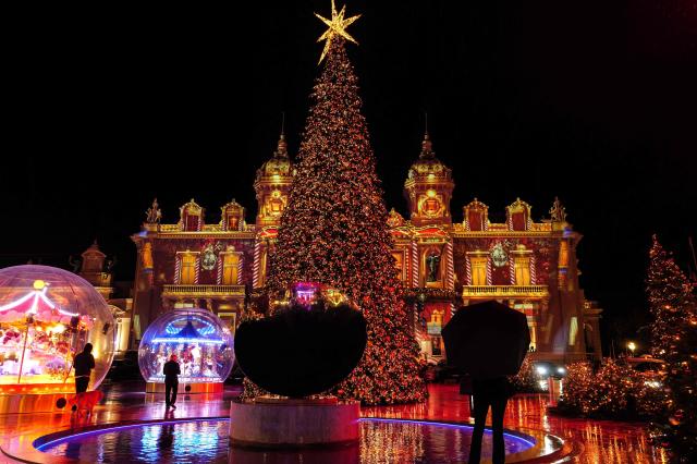 Visitors look at the Christmas tree displayed in the square in front of the Monte-Carlo Casino and the Hotel de Paris as part of the Christmas illuminations and decorations, in Monaco, on December 3, 2025. (Photo by Valery HACHE / AFP)