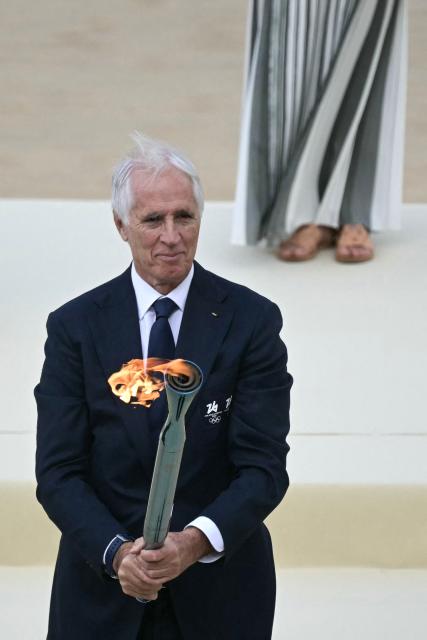 President of the Italian National Olympic Committee and CEO of the Milan Cortina 2026 Winter Olympic Giovanni Malago hands the torch during the handover Olympic flame ceremony for the Milano-Cortina 2026 Winter Olympic Games and Paralympic Games, at the Panathinean stadium in Athens, on December 4, 2025. (Photo by Angelos Tzortzinis / AFP)