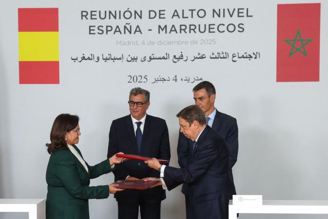 Spain's Agriculture Minister Luis Planas (R front) and Secretary of State at the Ministry of Agriculture, Fisheries and Rural Development, responsible for fisheries, Driouich Zakia (L) exchange accords during a signing ceremony attended by Spain's Prime Minister Pedro Sanchez (R) and Morocco's Prime Minister Aziz Akhannouch at the Moncloa Palace in Madrid on December 4, 2025. (Photo by Pierre-Philippe MARCOU / AFP)