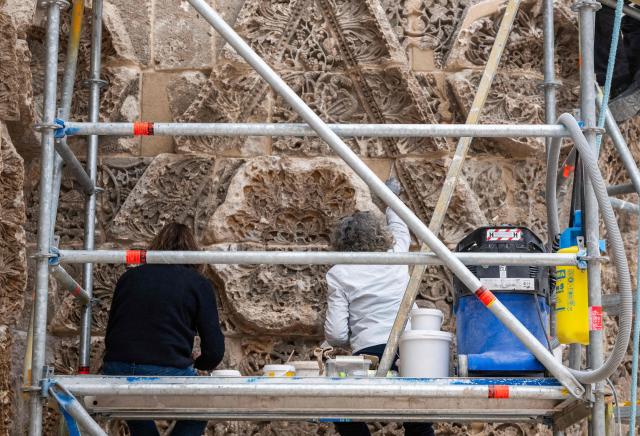 Restauration experts work on the 8th Century Mshatta Facade in the Islamic Art section as renovation work continues at the Pergamon Museum, in Berlin on December 4, 2025. With the first construction phase completed, the Collection of Classical Antiquities, Museum of Islamic Art, and Museum of the Ancient Near East are expected to reopen to the public  in spring 2027. The Pergamon Museum's complete renovation is expected to be finished in 2037. (Photo by John MACDOUGALL / AFP)