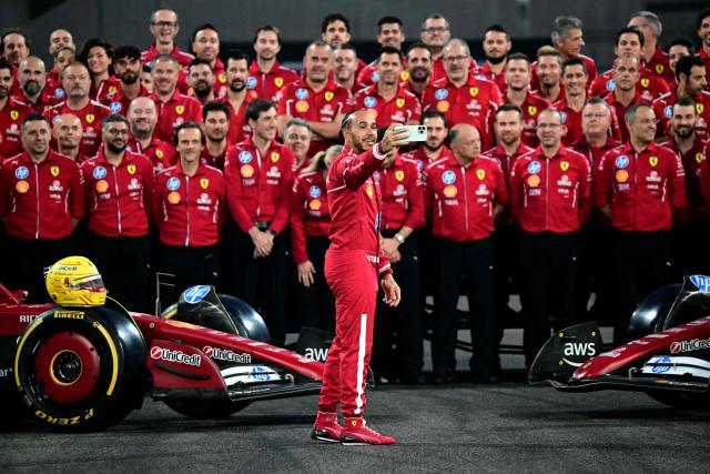 TOPSHOT - Ferrari's British driver Lewis Hamilton takes a photo of the team after a group photo session ahead of the Abu Dhabi Formula One Grand Prix at the Yas Marina Circuit in Abu Dhabi on December 4, 2025. (Photo by Giuseppe CACACE / AFP)