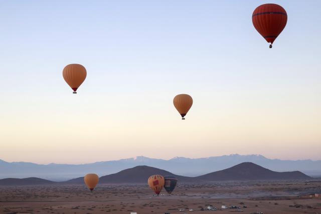 Hot air balloons fly over the Haouz plain in the the Oulad Hassoune region, a vast area north of Marrakech on December 4, 2025. (Photo by Abdel Majid BZIOUAT / AFP)