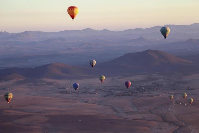 Hot air balloons fly over the Haouz plain in the the Oulad Hassoune region, a vast area north of Marrakech on December 4, 2025. (Photo by Abdel Majid BZIOUAT / AFP)