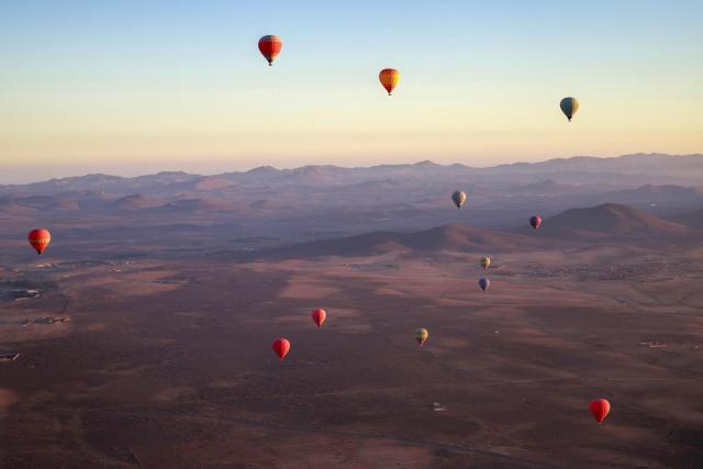 TOPSHOT - Hot air balloons fly over the Haouz plain in the the Oulad Hassoune region, a vast area north of Marrakech on December 4, 2025. (Photo by Abdel Majid BZIOUAT / AFP)