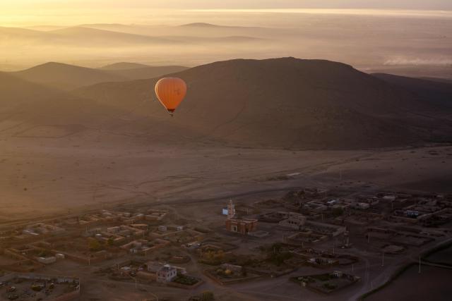 A hot air balloon flies over the Haouz plain in the the Oulad Hassoune region, a vast area north of Marrakech on December 4, 2025. (Photo by Abdel Majid BZIOUAT / AFP)