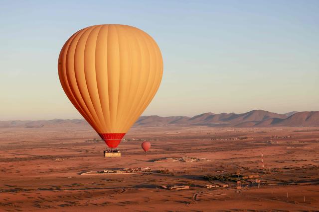 TOPSHOT - Hot air balloons fly over the Haouz plain in the the Oulad Hassoune region, a vast area north of Marrakech on December 4, 2025. (Photo by Abdel Majid BZIOUAT / AFP)
