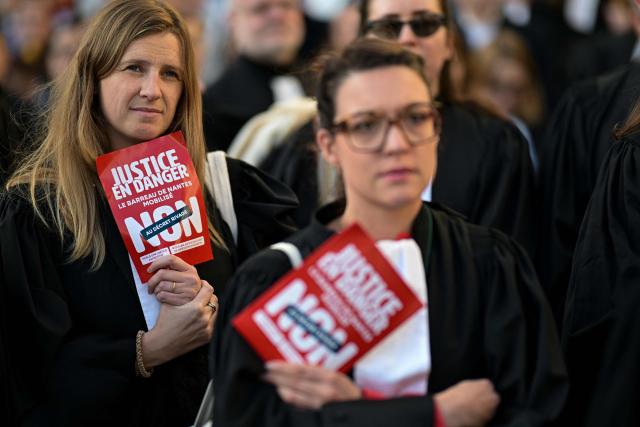 Protesters hold pamphlets reading "Justice in danger - Nantes Bar Association takes action - No to the "RIVAGE" decree" as lawyers gather during a demonstration in front of the Rennes' Court of Appeal to protest against the proposed "RIVAGE" decree (Rationalisation of Appeal Proceedings to Ensure Efficiency) in Rennes, western France, on December 4, 2025. (Photo by Damien MEYER / AFP)