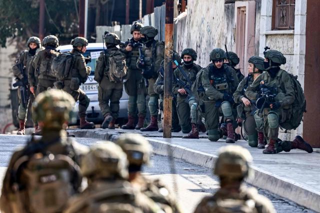 Israeli soldiers take positions during a military operation in the town of Qalqiya, in the occupied West Bank on December 4, 2025. (Photo by Zain JAAFAR / AFP)