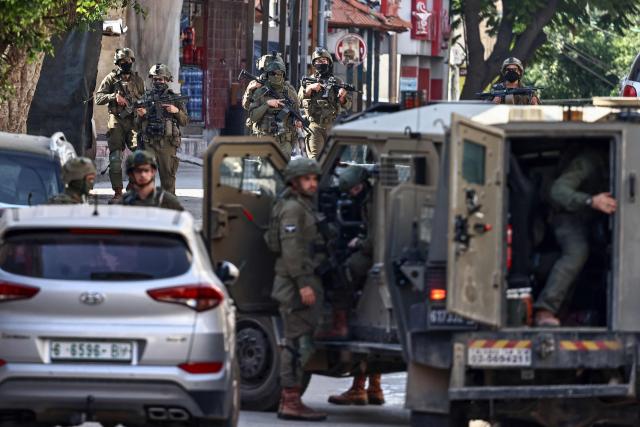 Israeli soldiers take positions during a military operation in the town of Qalqiya, in the occupied West Bank on December 4, 2025. (Photo by Zain JAAFAR / AFP)