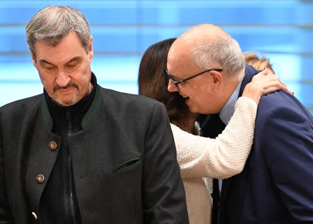 Bavaria's State Premier Markus Soeder (L) looks on as Bremen's mayor Andreas Bovenschulte (R) is hugged by German Minister for Research, Technology and Aerospace Dorothee Baer at the start of a meeting of the leaders of the country's federal states with the German Chancellor on December 4, 2025 at the Chancellery in Berlin. (Photo by RALF HIRSCHBERGER / AFP)