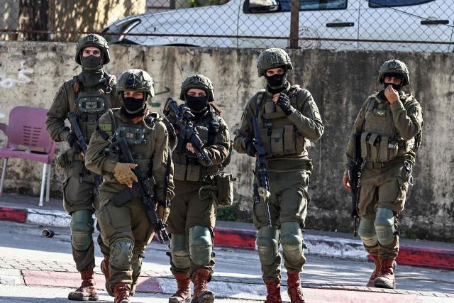 Israeli soldiers walk during a military operation in the town of Qalqiya, in the occupied West Bank on December 4, 2025. (Photo by Zain JAAFAR / AFP)
