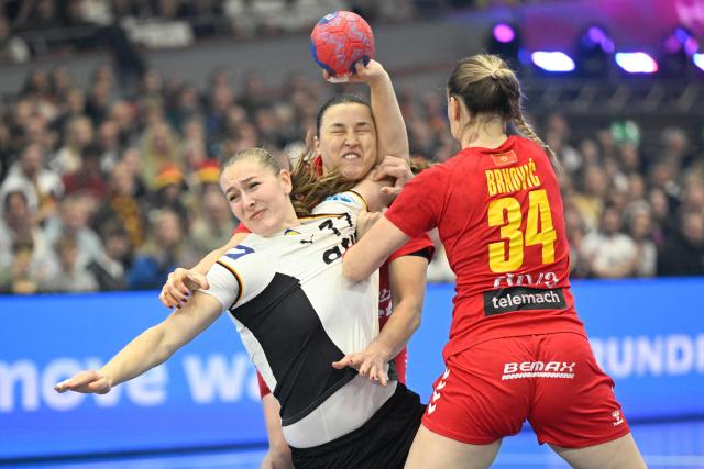 Germany's right back #77 Viola Leuchter shoots over Montenegro's left back #09 Djurdjina Jaukovic and Montenegro's pivot #34 Tatjana Brnovic during the main round - Day 5 Group II handball match Montenegro v Germany of the IHF Women's Handball World Championship in Dortmund, western Germany on December 4, 2025. (Photo by INA FASSBENDER / AFP)