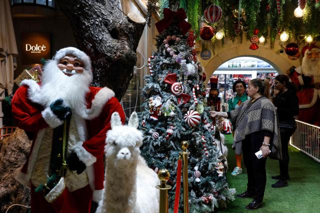 A woman looks at a Christmas tree at a market in the German Colony area in Haifa on December 4, 2025. (Photo by Jalaa MAREY / AFP)