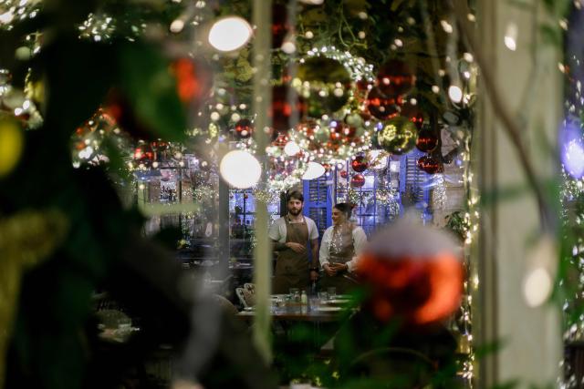 Waiters stand at a table in a restaurant adorned with Christmas decorations at the German Colony area in Haifa on December 4, 2025. (Photo by Jalaa MAREY / AFP)