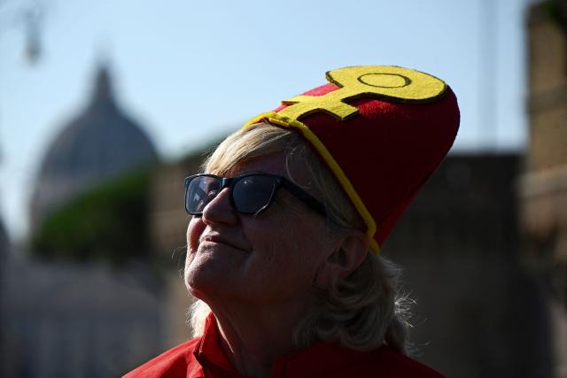 (FILES) A supporter of Women's Ordination Conference (WOC), dressed as a Pope with red vestments, takes part in a demonstration to advocate and pray for the ordination of women as deacons, priests, and bishops into an inclusive and accountable Roman Catholic Church, near the Vatican in Rome on October 6, 2023. A Vatican commission has yet to take a firm decision on whether women could become deacons, but the answer for now remains no, according to a document made public on December 4, 2025. (Photo by Filippo MONTEFORTE / AFP)