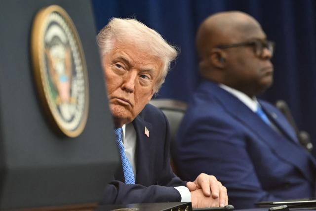 US President Donald Trump (C) looks on during the signing ceremony of a peace deal with the President of Rwanda Paul Kagame (out of frame) and the President of the Democratic Republic of the Congo Felix Tshisekedi (R) at the United States Institute of Peace in Washington, DC, on December 4, 2025. Trump on Thursday brings the leaders of Rwanda and the Democratic Republic of Congo together to endorse a deal that Trump has hailed as his latest peace triumph despite ongoing violence on the ground. Trump hopes the agreement will pave the way for the United States to gain access to critical minerals in the eastern DRC, a violence-torn region home to many of the key ingredients in modern technologies such as electric cars. (Photo by ANDREW CABALLERO-REYNOLDS / AFP)
