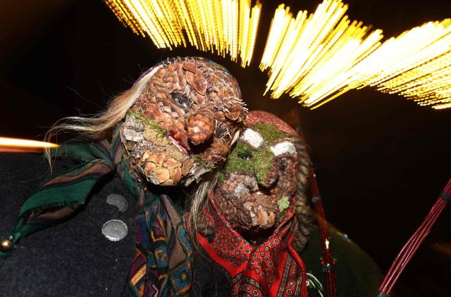 So-called 'Baerbele' women wear masks made of natural materials as they take part in the traditional ' Baerbele walk' in Sonthofen, southern Germany, on December 4, 2025. During the Baerbele tradition in the Allgau region, southern Germany, unmarried women dress up with masks and rag on Saint Barbara's Day, adorned with bells, walk from house to house. (Photo by Karl-Josef Hildenbrand / AFP)