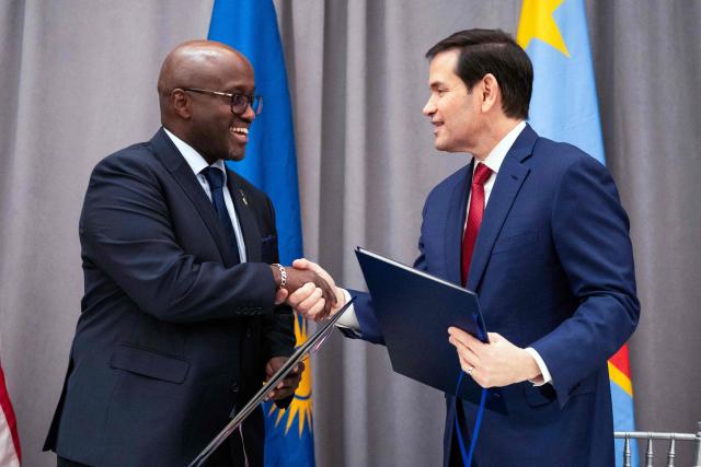 US Secretary of State Marco Rubio (R) and Rwandan Foreign Minister Olivier Nduhungirehe shake hands during a signing ceremony at the US Institute of Peace in Washington, DC on December 4, 2025. US President Donald Trump on Thursday brings the leaders of Rwanda and the Democratic Republic of Congo together to endorse a deal that Trump has hailed as his latest peace triumph despite ongoing violence on the ground. Trump hopes the agreement will pave the way for the United States to gain access to critical minerals in the eastern DRC, a violence-torn region home to many of the key ingredients in modern technologies such as electric cars. (Photo by Allison ROBBERT / AFP)