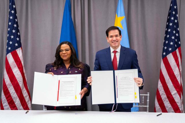 US Secretary of State Marco Rubio (R) and the Foreign Minister of the Democratic Republic of the Congo Therese Kayikwamba Wagner pose with signed agreements during a ceremony at the US Institute of Peace in Washington, DC on December 4, 2025. US President Donald Trump on Thursday brings the leaders of Rwanda and the Democratic Republic of Congo together to endorse a deal that Trump has hailed as his latest peace triumph despite ongoing violence on the ground. Trump hopes the agreement will pave the way for the United States to gain access to critical minerals in the eastern DRC, a violence-torn region home to many of the key ingredients in modern technologies such as electric cars. (Photo by Allison ROBBERT / AFP)