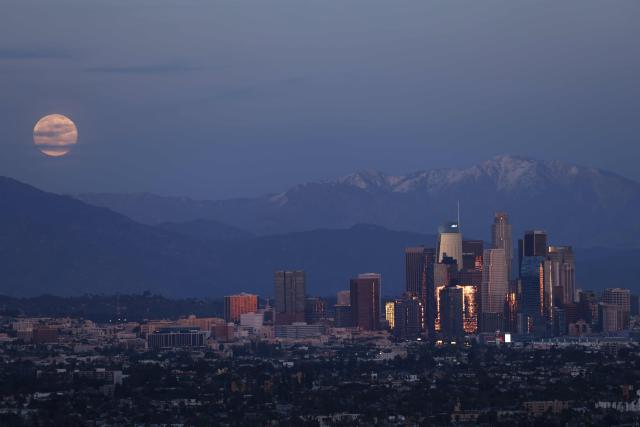 The last supermoon of 2025, the Cold Moon, rises behind the snow-capped San Gabriel Mountains and the Los Angeles skyline as seen from Kenneth Hahn State Recreation Area on December 4, 2025. (Photo by Patrick T. Fallon / AFP)