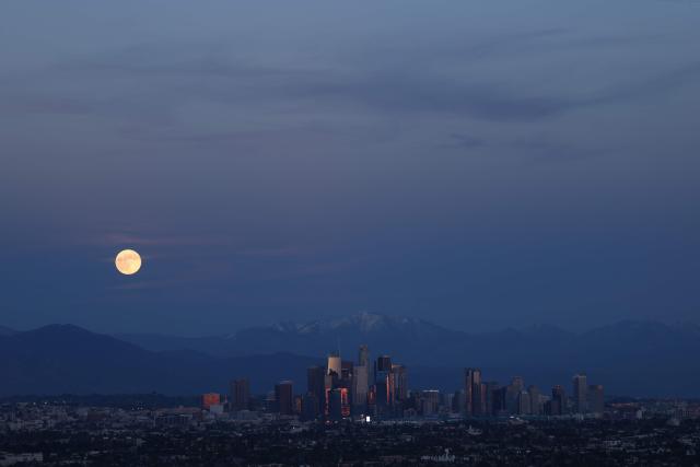 The last supermoon of 2025, the Cold Moon, rises behind the snow-capped San Gabriel Mountains and the Los Angeles skyline as seen from Kenneth Hahn State Recreation Area on December 4, 2025. (Photo by Patrick T. Fallon / AFP)