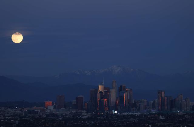The last supermoon of 2025, the Cold Moon, rises behind the snow-capped San Gabriel Mountains and the Los Angeles skyline as seen from Kenneth Hahn State Recreation Area on December 4, 2025. (Photo by Patrick T. Fallon / AFP)
