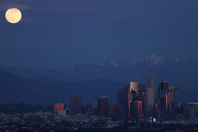 The last supermoon of 2025, the Cold Moon, rises behind the snow-capped San Gabriel Mountains and the Los Angeles skyline as seen from Kenneth Hahn State Recreation Area on December 4, 2025. (Photo by Patrick T. Fallon / AFP)