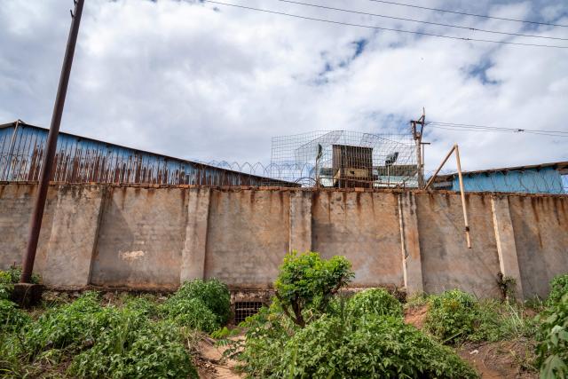 A general view of the outside walls of the Chinese mining company Congo Dongfang Mining (CDM)in Lubumbashi on November 24, 2025. Her parched field is overrun with debris carried by polluted waters, and the little girl in his arms is covered in sores: in Lubumbashi, the mining capital of the DRC, thousands of Congolese claim to be victims of toxic waste from the mining industry. Hélène Mvubu recounts enduring for years the effects of floods caused by contaminated water discharged by Congo Dongfang Mining (CDM), a Chinese mining company that processes copper and cobalt ores in the outskirts of the capital of Katanga province, in the southeastern Democratic Republic of Congo (DRC). (Photo by Glody MURHABAZI / AFP)