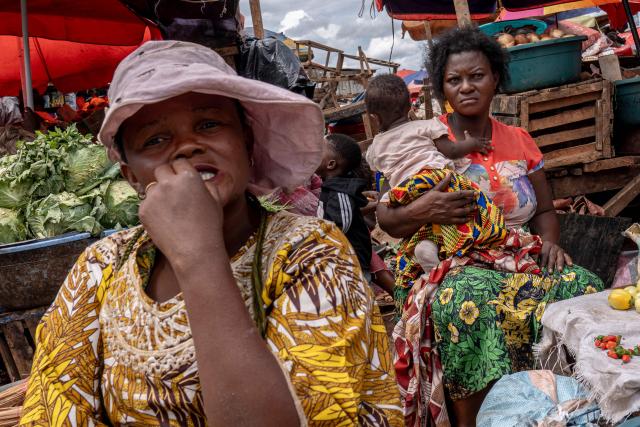 Women sells their goods at a market in Lubumbashi on November 24, 2025. Her parched field is overrun with debris carried by polluted waters, and the little girl in his arms is covered in sores: in Lubumbashi, the mining capital of the DRC, thousands of Congolese claim to be victims of toxic waste from the mining industry. Hélène Mvubu recounts enduring for years the effects of floods caused by contaminated water discharged by Congo Dongfang Mining (CDM), a Chinese mining company that processes copper and cobalt ores in the outskirts of the capital of Katanga province, in the southeastern Democratic Republic of Congo (DRC). (Photo by Glody MURHABAZI / AFP)