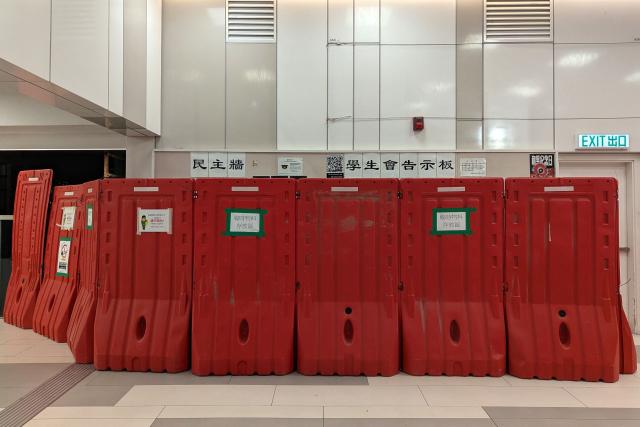A general view shows barricades in front of the student union-run notice board, nicknamed “democracy wall”, at Hong Kong Baptist University in Hong Kong on December 3, 2025. A Hong Kong university ordered its student union to shut down after a message was posted on campus expressing condolences and urging justice for the victims of a major fire, according to a letter publicly shared on December 5. A message expressing condolences and urging justice for the victims in a deadly fire at Wang Fuk Court was seen on the notice board before it was blocked off. (Photo by Holmes CHAN / AFP)