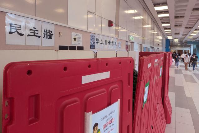 A general view shows barricades in front of the student union-run notice board, nicknamed “democracy wall”, at Hong Kong Baptist University in Hong Kong on December 3, 2025. A Hong Kong university ordered its student union to shut down after a message was posted on campus expressing condolences and urging justice for the victims of a major fire, according to a letter publicly shared on December 5. A message expressing condolences and urging justice for the victims in a deadly fire at Wang Fuk Court was seen on the notice board before it was blocked off. (Photo by Holmes CHAN / AFP)