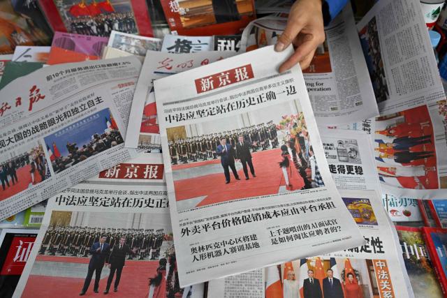 This picture shows newspaper front pages featuring the visit of France's President Emmanuel Macron and his wife Brigitte Macron in Beijing on December 5, 2025. (Photo by Adek BERRY / AFP)