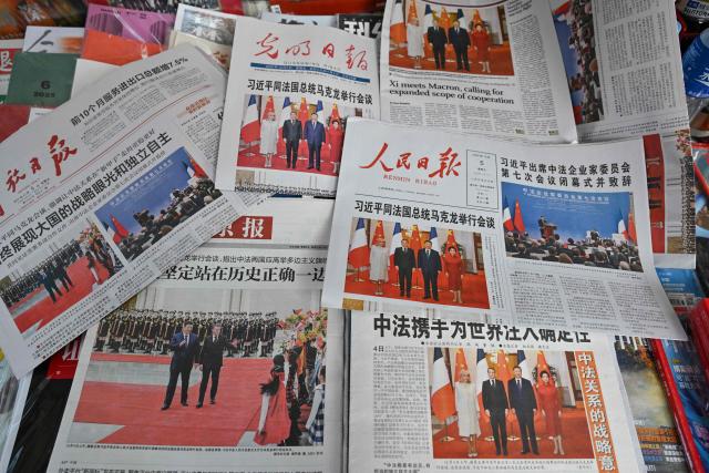 This picture shows newspaper front pages featuring the visit of France's President Emmanuel Macron and his wife Brigitte Macron in Beijing on December 5, 2025. (Photo by Adek BERRY / AFP)