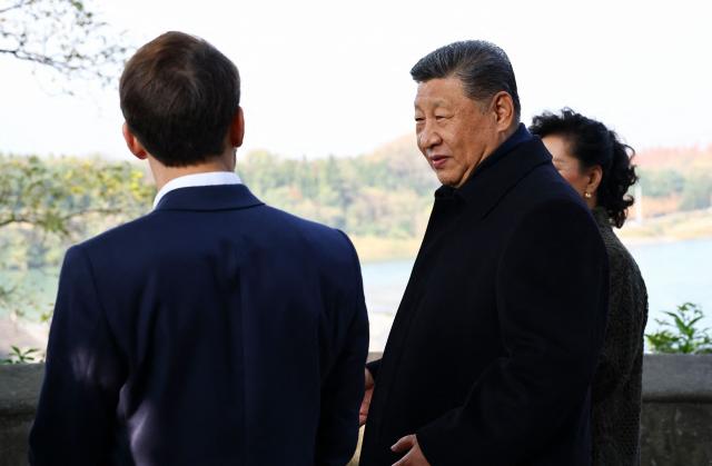 French President Emmanuel Macron (L), Chinese President Xi Jinping (C) and his wife Peng Liyuan (R) visit the Dujiangyan site, a designated UNESCO World Heritage site, in Dujiangyan, in southwestern China's Sichuan province on December 5, 2025. (Photo by Sarah Meyssonnier / POOL / AFP)