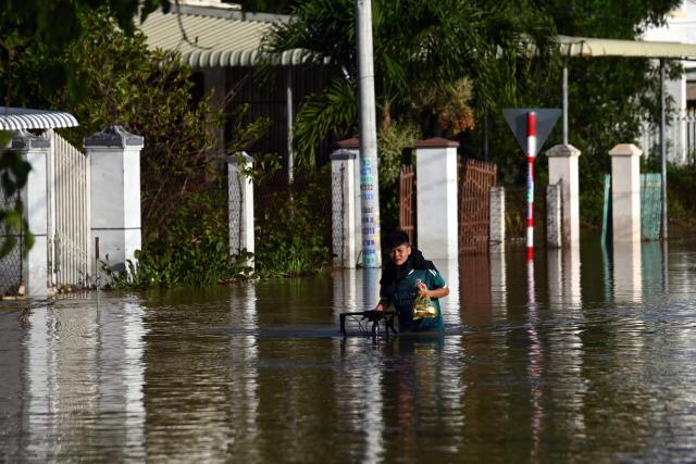 A man walks with his bicycle through flood waters on a street in Vietnam's Lam Dong province on December 5, 2025, following weeks of heavy rain. South-central Vietnam has been lashed by weeks of heavy rain, submerging hundreds of thousands of homes in popular coastal tourism hotspots and causing deadly landslides in mountainous regions. (Photo by Quoc Nguyen / AFP)