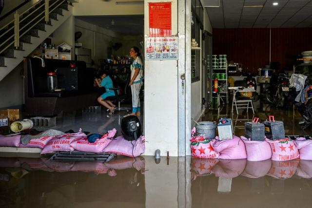 Residents look on as sandbags block flood waters at the entrance to a house in Vietnam's Lam Dong province on December 5, 2025, following weeks of heavy rain. South-central Vietnam has been lashed by weeks of heavy rain, submerging hundreds of thousands of homes in popular coastal tourism hotspots and causing deadly landslides in mountainous regions. (Photo by Quoc Nguyen / AFP)