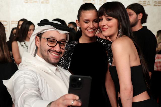 US actress Dakota Johnson (R) and Candian actress Nina Dobrev pose for a photo with a fan as they arrive during the opening ceremony of the 5th edition of the Red Sea Film Festival in Jeddah on December 4, 2025. (Photo by PATRICK BAZ / Factstory for the Red Sea International Festival (RSFF) / AFP)